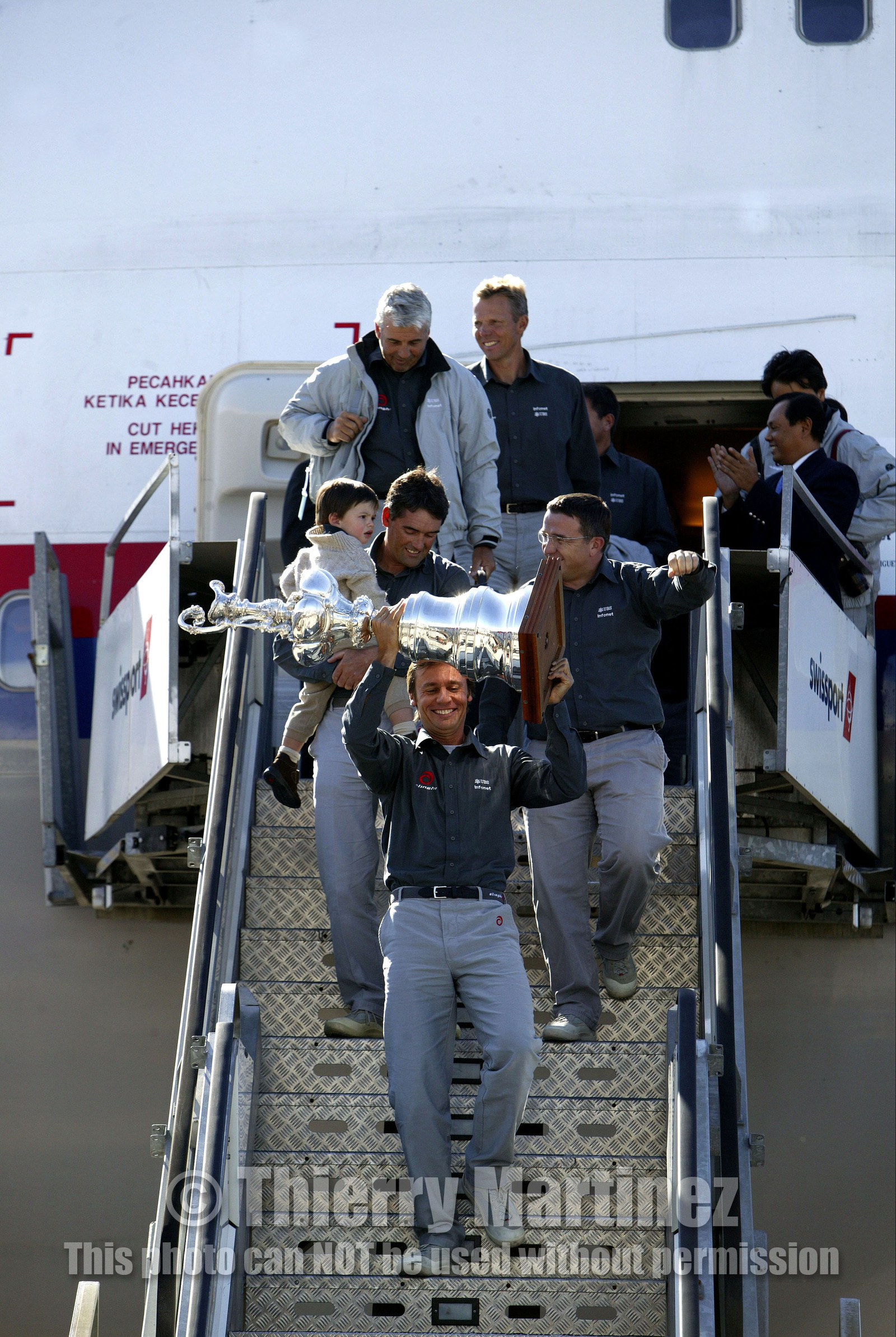 03_2209D ©Th.Martinez Team .Geneva , Switzerland. America's Cup 2003. 8th March 2003.Alinghi Team winner of America's Cup 2003, arriving in Geneva Airport with thE America's Cup. Alinghi 's President and navigator holding the America's Cup, and folowed bt Russell Coutts (with his son Michael) and Michel Bonnefous, Brad Butterworth and Jochen Schuemann.They are arriving in Geneva airport by a specia lplane from Auckland. First time since the first Regatta in 1851 that the America's Cup is going back to Europe....