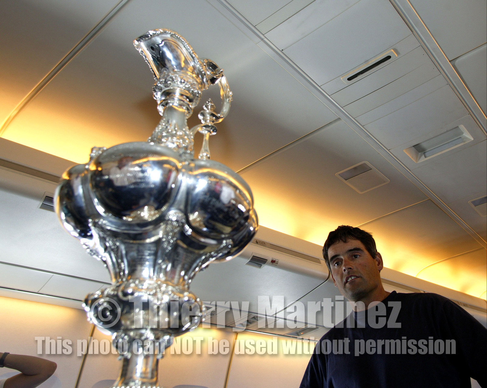 03_2200D ©Th.Martinez - Airplane (Auckland to Geneva) . America's Cup 2003. 8th March 2003.Alinghi Team winner of America's Cup 2003..Alinghi's skipper Russell Coutts looking at the trophy  he won tree time in a row, in the plane back to Geneva....