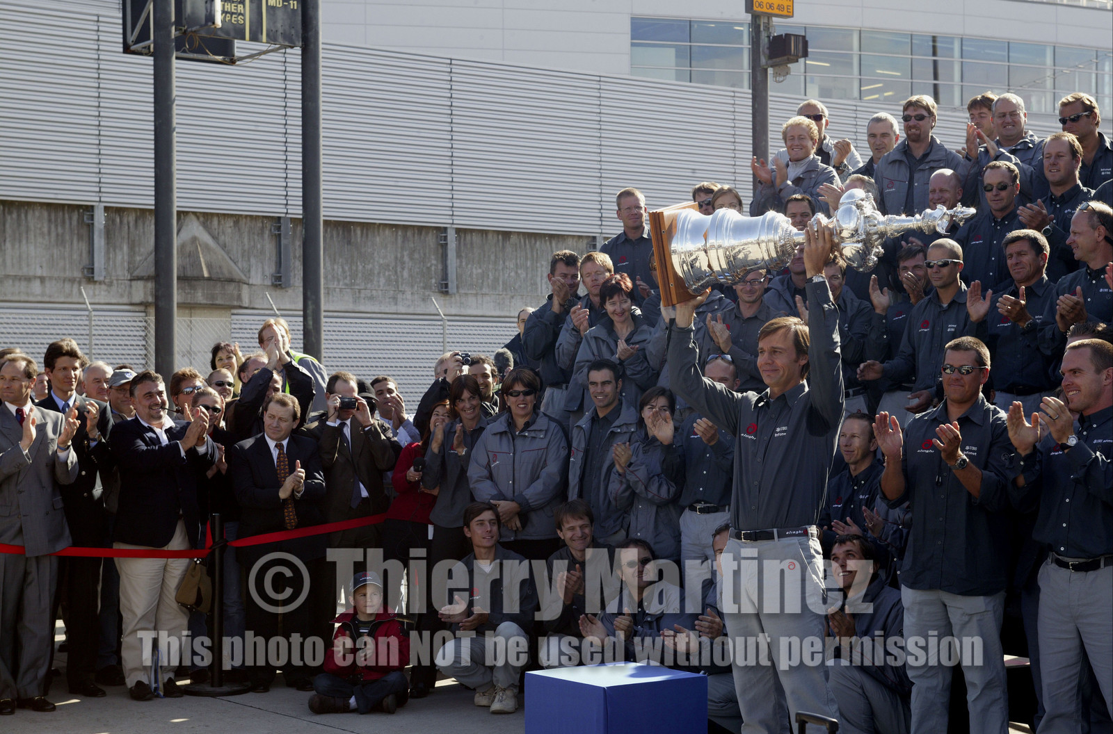 03_2215D ©Th.Martinez Team .Geneva , Switzerland. America's Cup 2003. 8th March 2003.Alinghi Team winner of America's Cup 2003, arriving in Geneva Airport with the America's Cup..Ernesto Bertraelli (Alinghi's president and navigator) holding up the Cup to media during welcome cermony at Geneva Airport with all Alinghi team behind him....