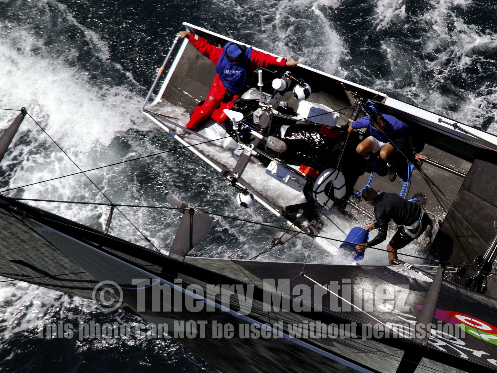 03_0183D ©Th.Martinez - Auckland (NZ) . America's Cup 2003. 15th February 2003. Day 1..Alinghi (SUI 64) vs Team NZ (NZL 82) .NZL 82 in first minutes of Race 1 before retiring on damage. Alinghi 1- Team NZ 0 .Matt Mitchell (Team NZ midbowman) bailing water out of NZL 82. .